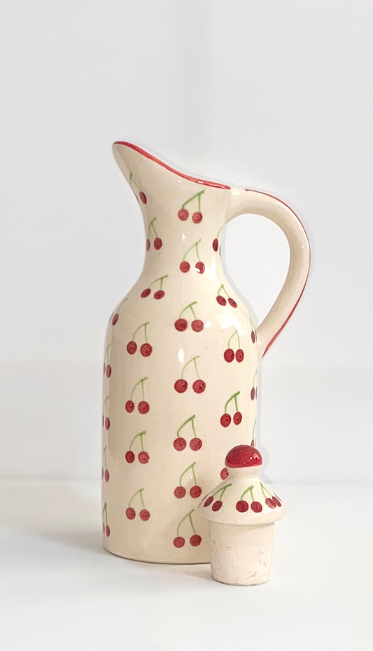 Cream-colored ceramic pitcher with cherry pattern on a white background