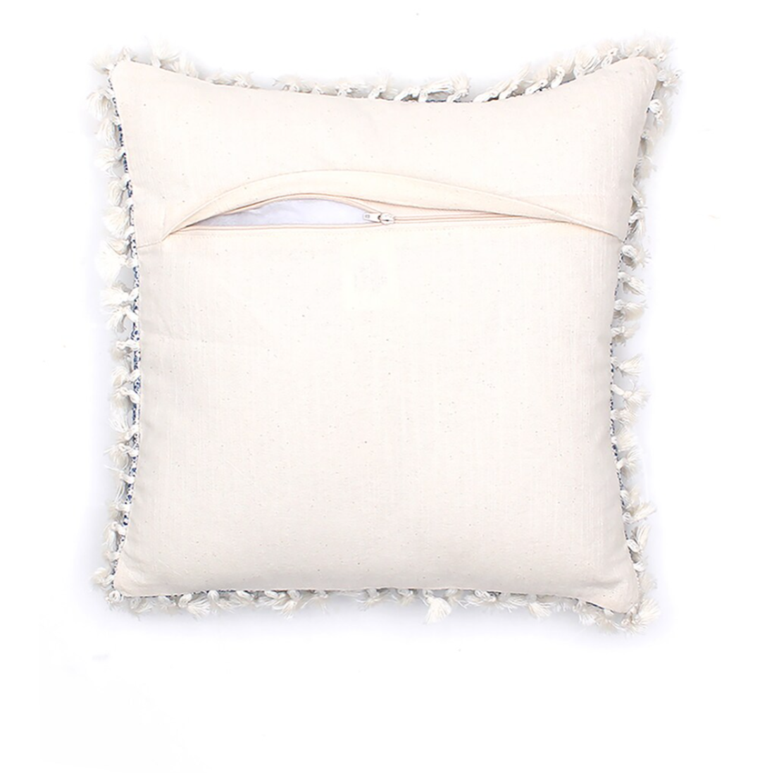 White pillow with decorative tassels on a white background