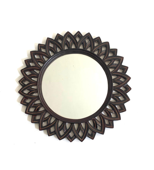 Decorative round mirror with intricate black floral frame on a white background