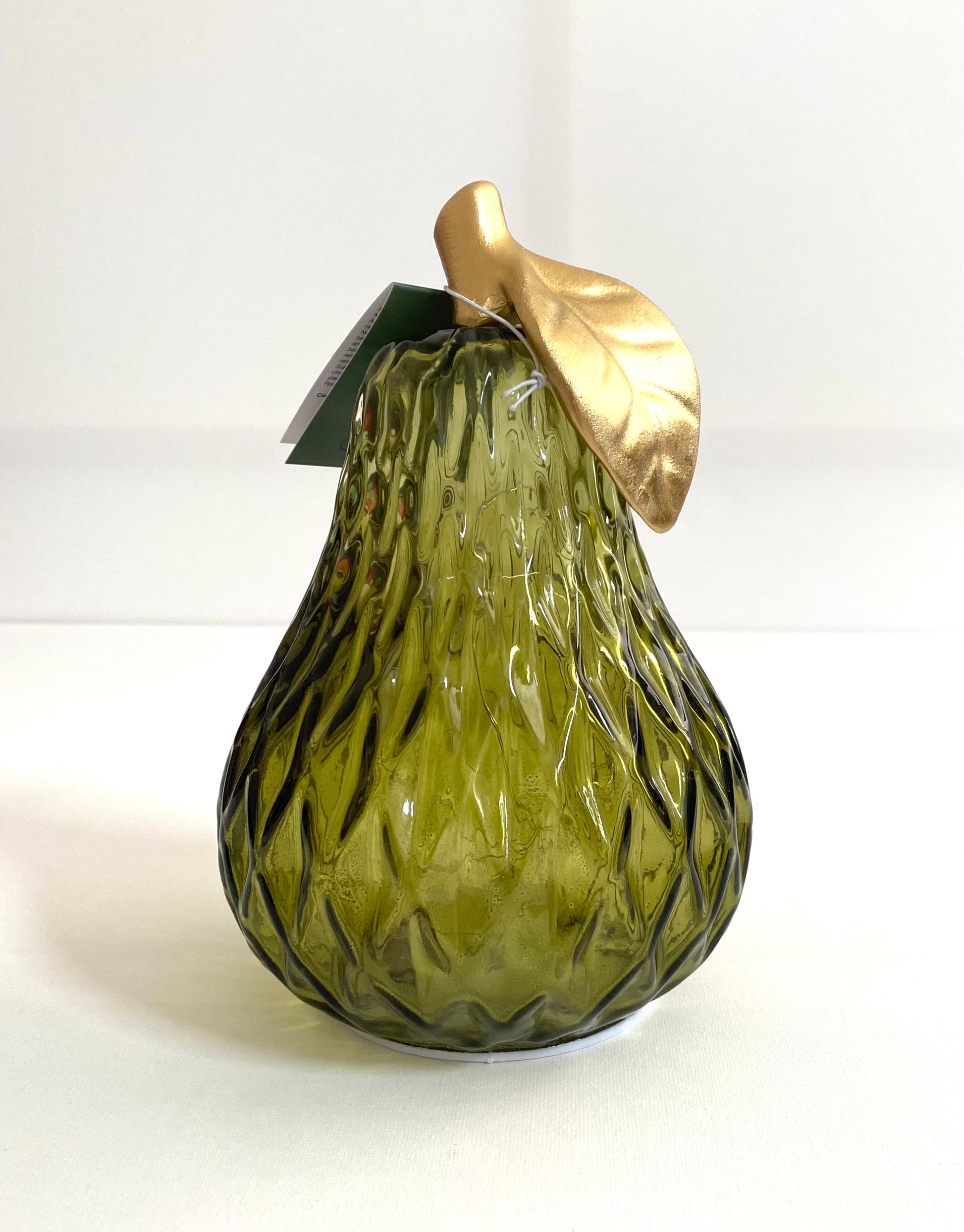 Green glass pear with a gold leaf on a white background