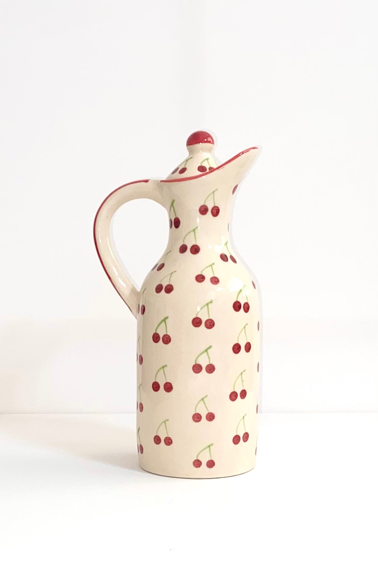 Ceramic pitcher with cherry pattern on a white background