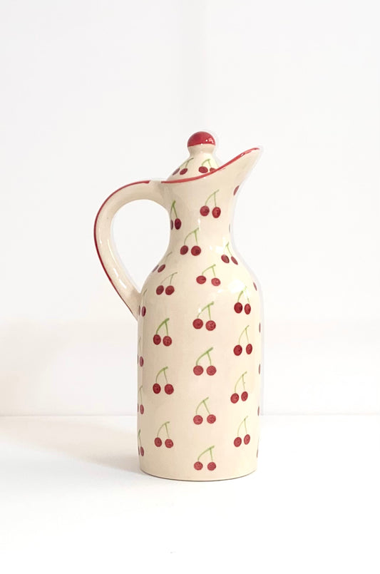 Ceramic pitcher with cherry pattern on a white background
