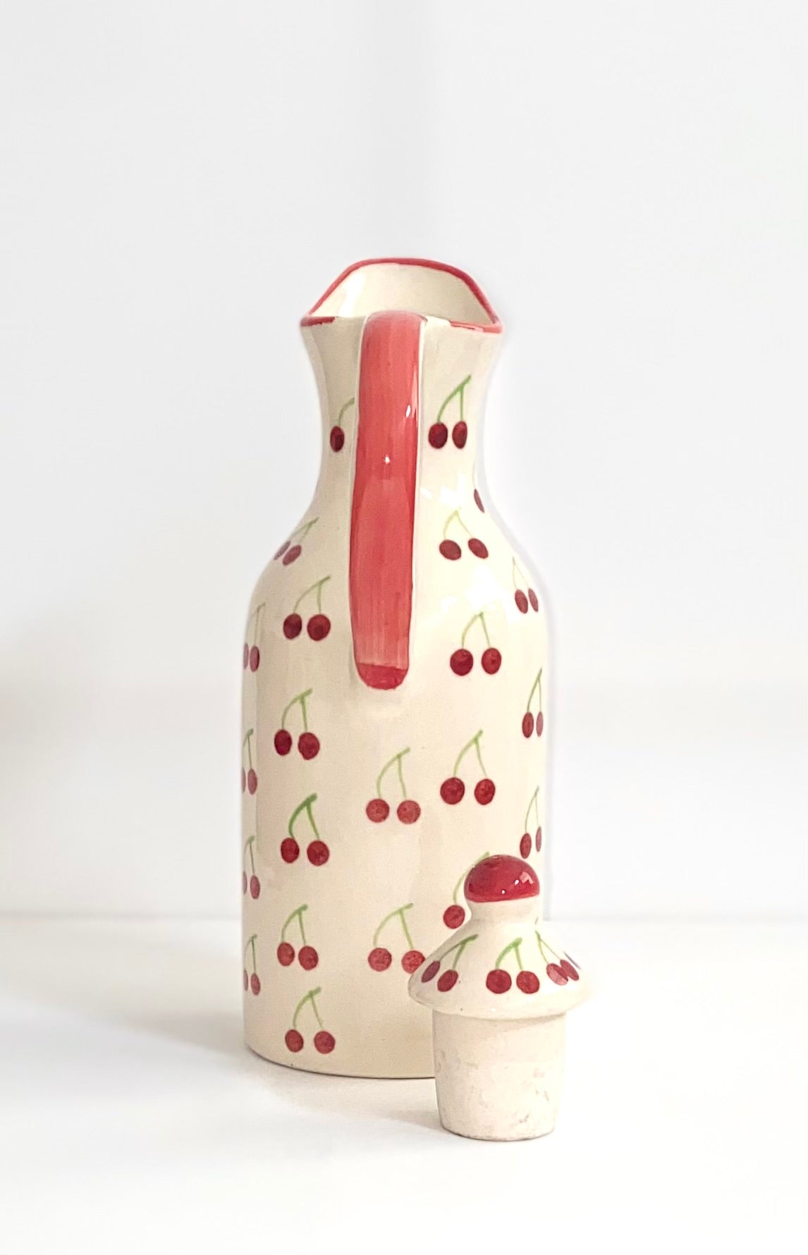 Ceramic pitcher with cherry design on a white background