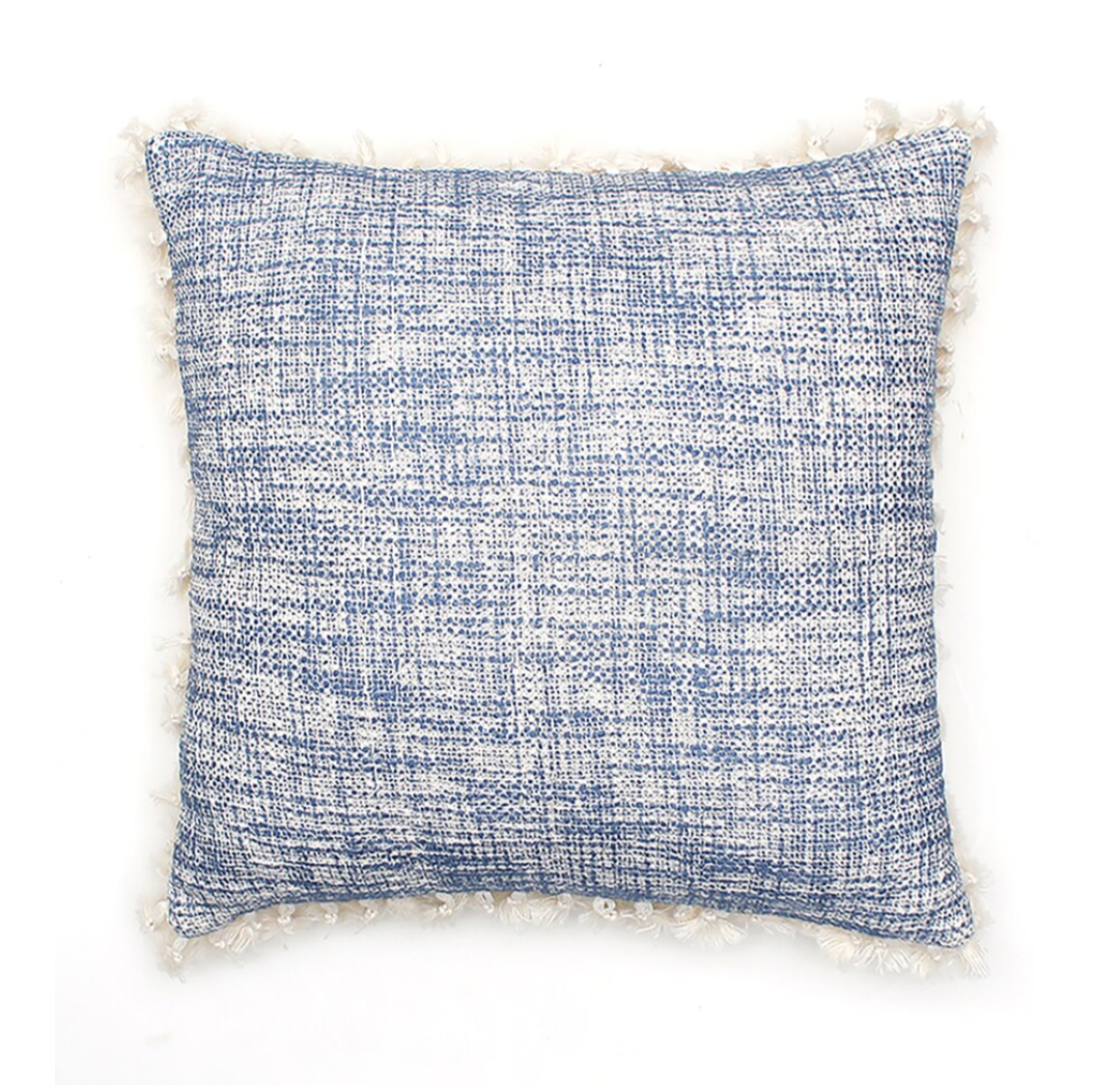Textured blue pillow with white fringes on a white background